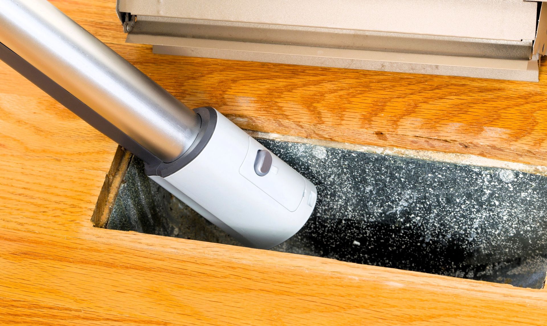 Vacuum hose cleaning a dusty air duct