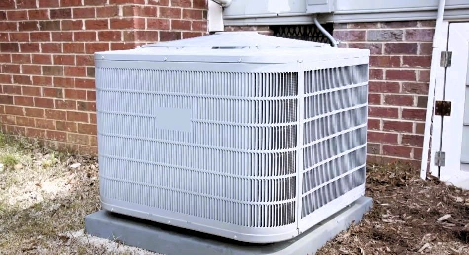 HVAC unit on concrete base by brick wall