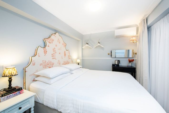 Bedroom with floral headboard, white bedding, blue walls, and side table with lamp.