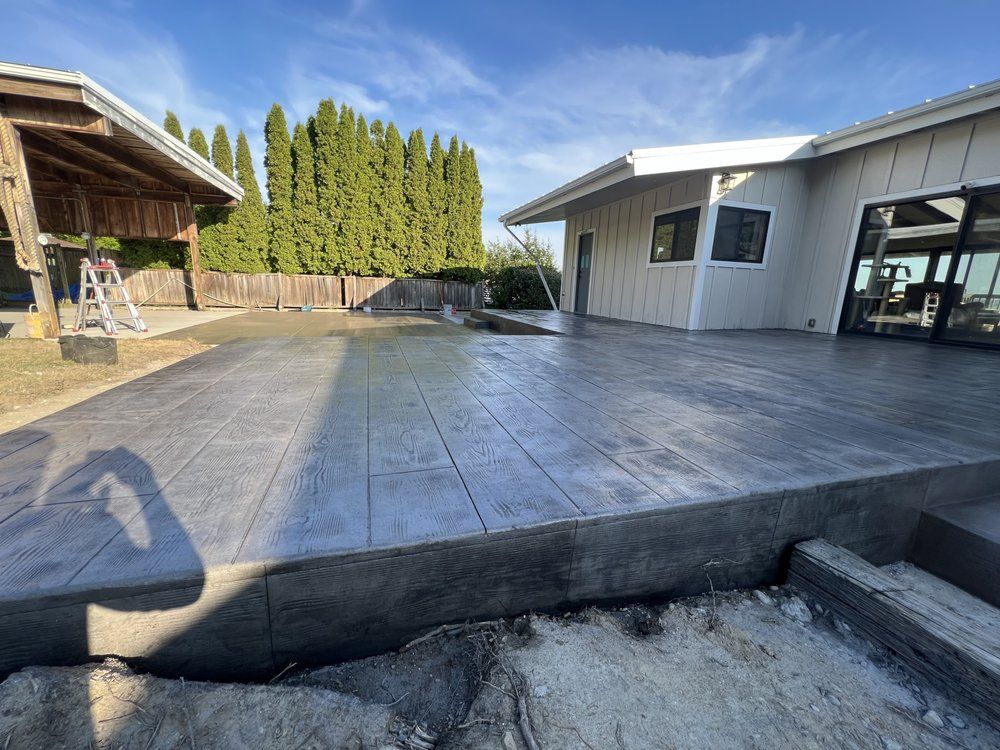 Backyard patio with stamped concrete, steps, and a covered outdoor seating area beside a house