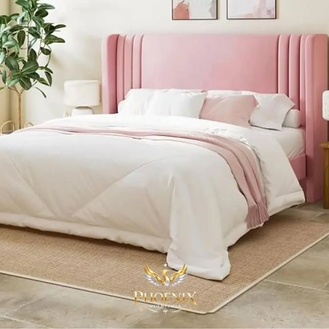 Cama tapizada de color rosa con ropa de cama y almohadas blancas en un dormitorio luminoso y minimalista
