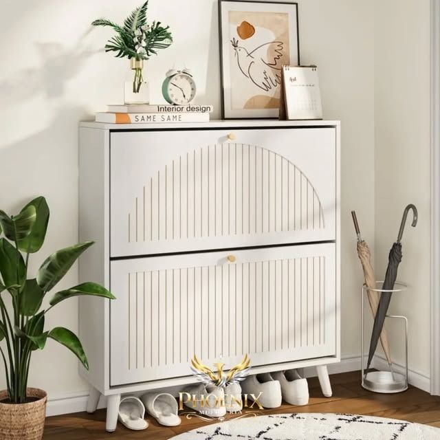 Armario blanco con puertas arqueadas, plantas, libros y objetos decorativos en una habitación luminosa de estilo minimalista.