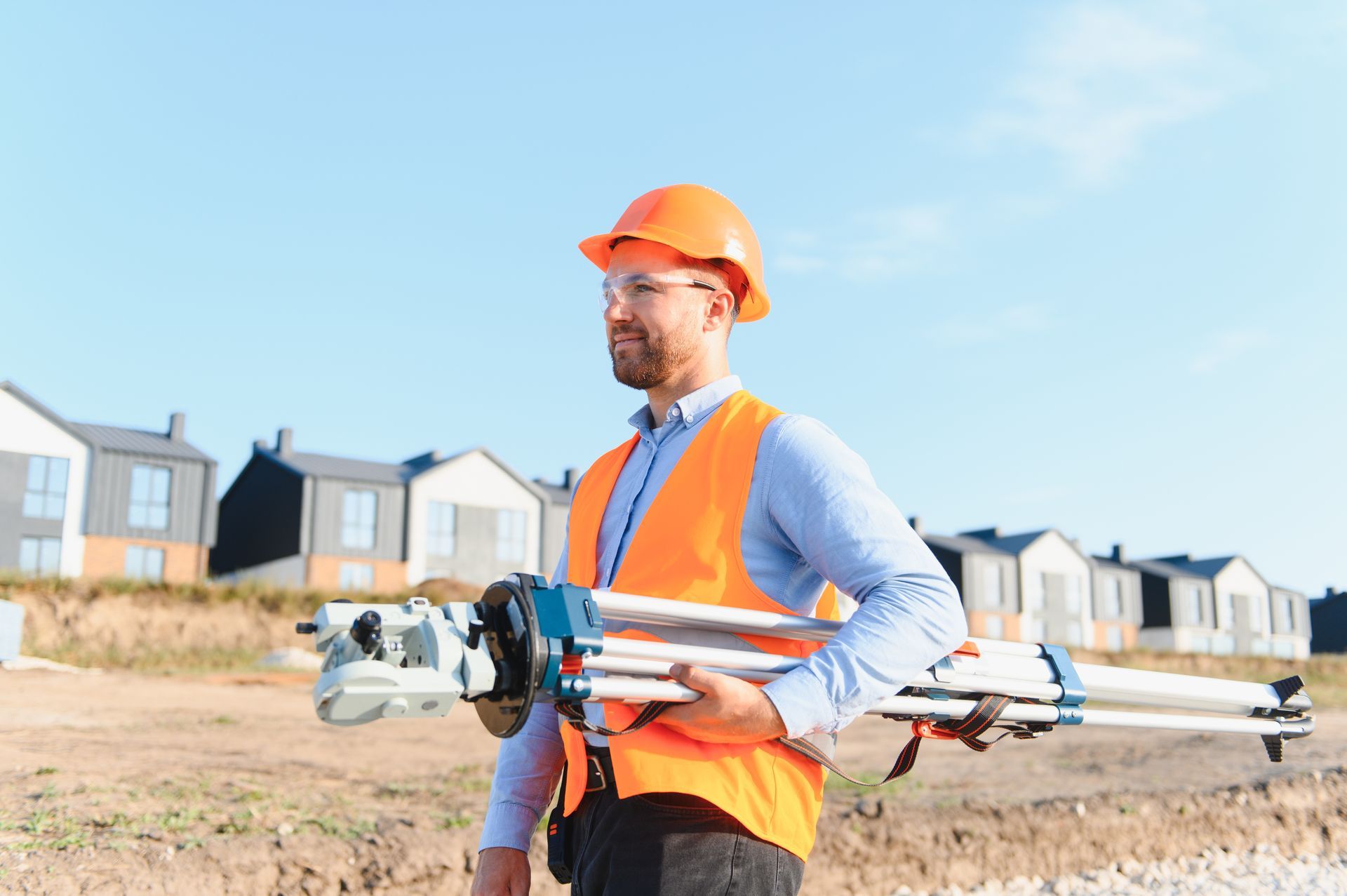Surveyor carrying total station at residential construction site. Surveyor carrying total station at residential construction site.