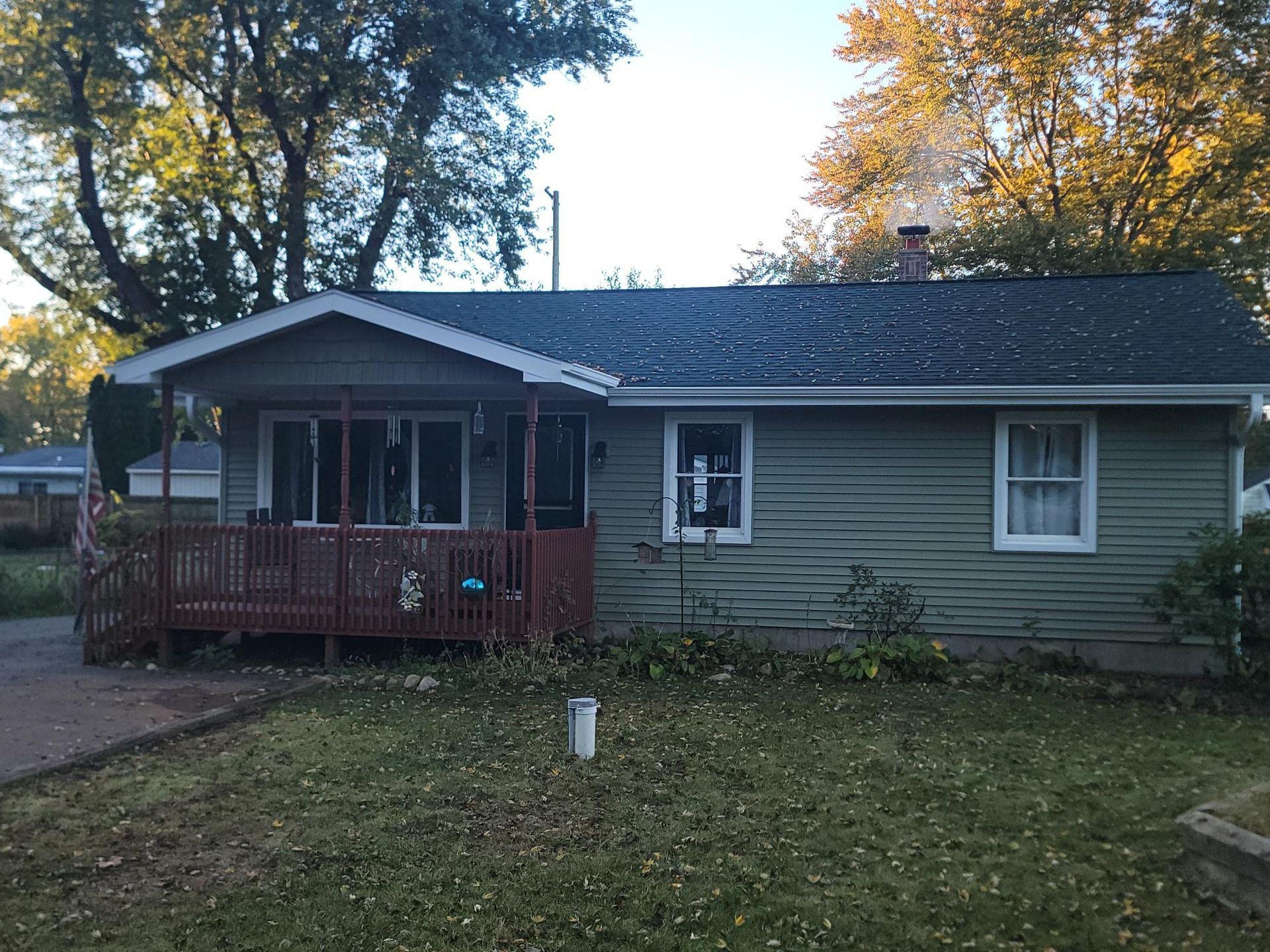 Single-story gray house with a red porch, framed by trees and a grassy yard.