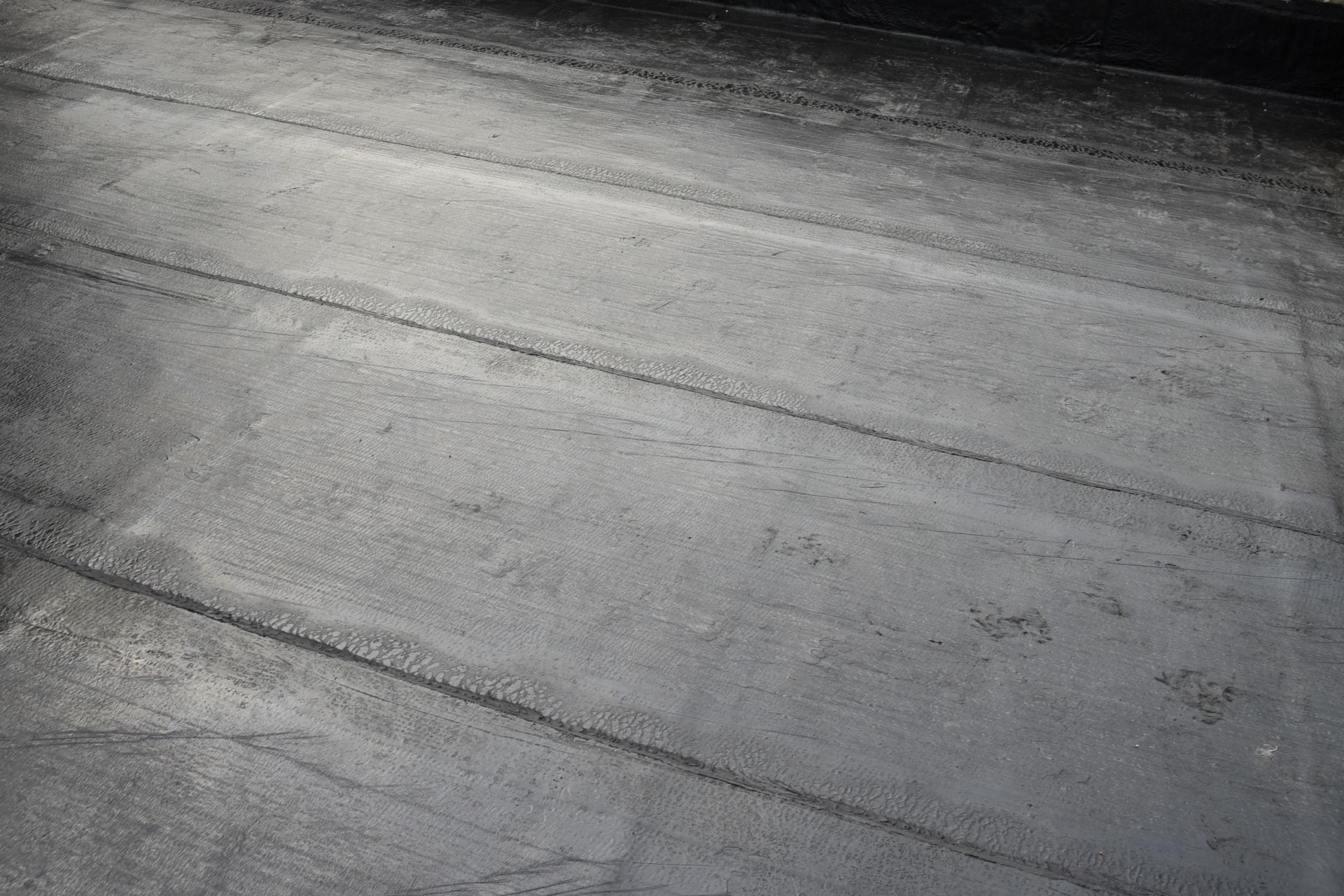Close-up of a textured gray concrete surface with diagonal seams and dark streaks