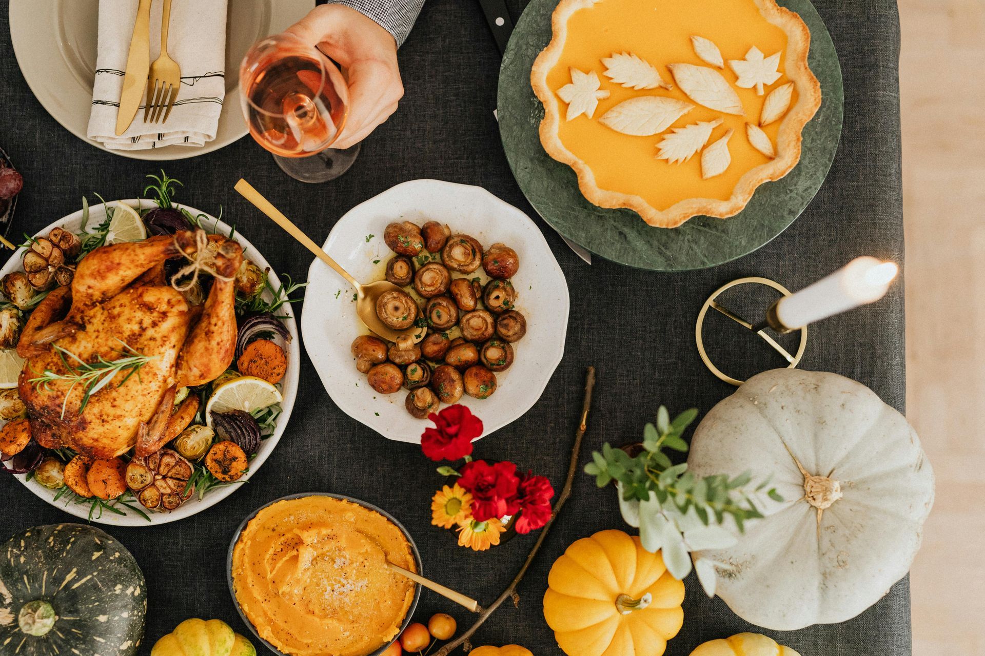 Top-down view of a Thanksgiving dinner table with roasted chicken, autumn vegetables, a pumpkin pie, and decorative gourds.