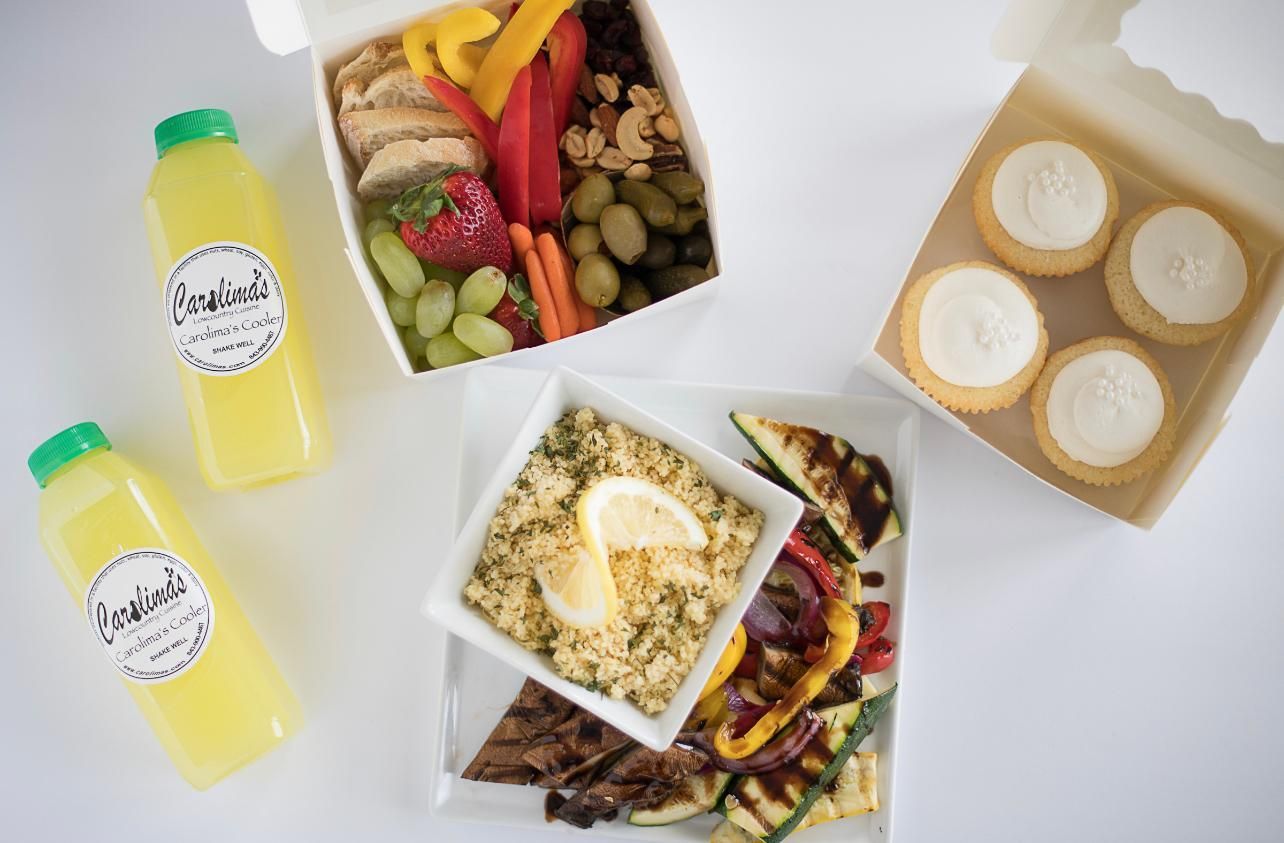 Assorted meal prep containers, salads, and two lemon drinks arranged on a white background