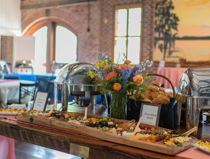 Buffet table with pastries, fruit, and flowers in a warmly lit rustic indoor venue
