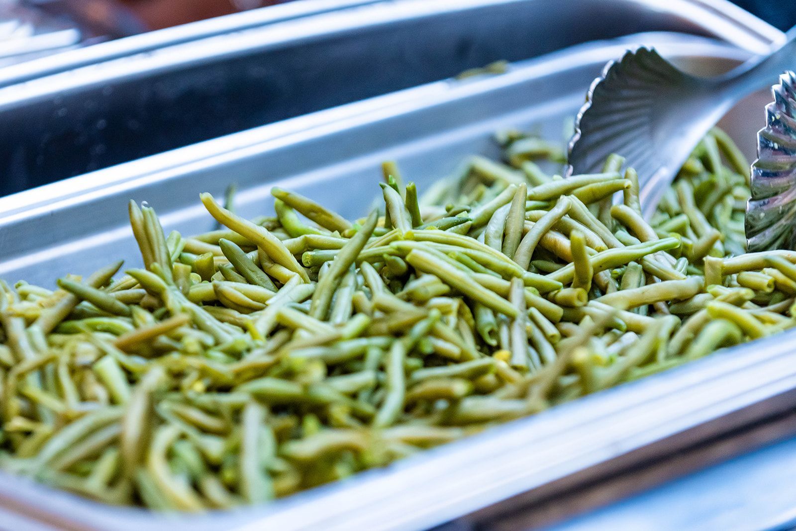 Tray of cooked green beans in a metal serving pan at a buffet