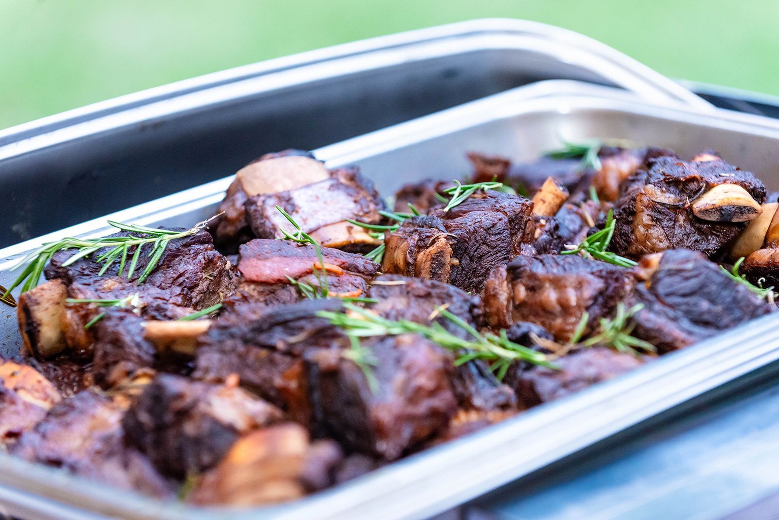 Roasted meat chunks with herbs in a metal tray on a table