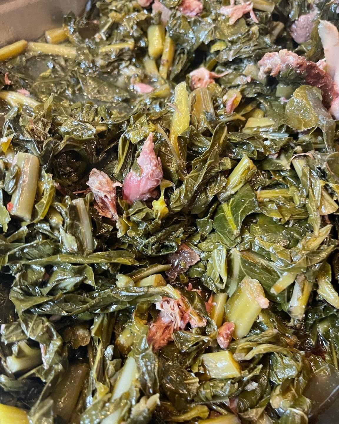 Cooked collard greens with pieces of ham in a bowl