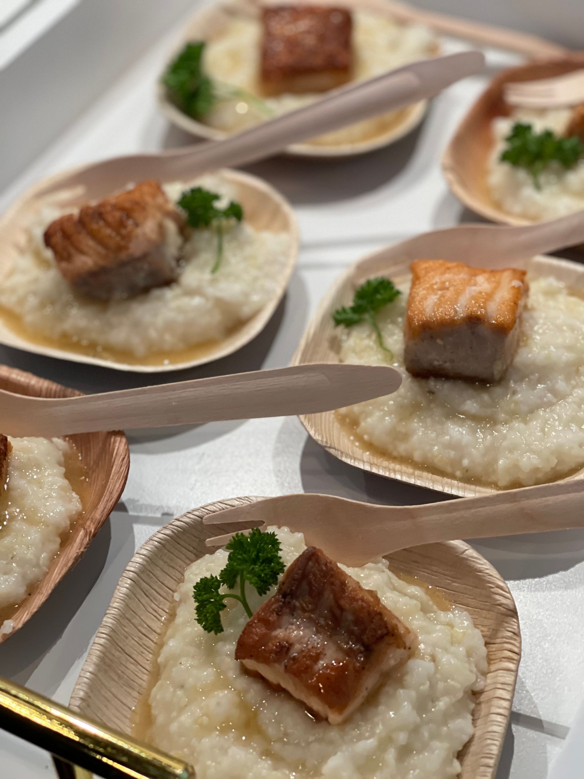 Small cups of creamy dessert topped with caramelized squares and parsley on a tray