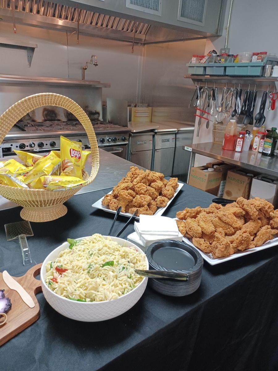 Buffet spread with fried chicken, salad, and bread in a restaurant kitchen