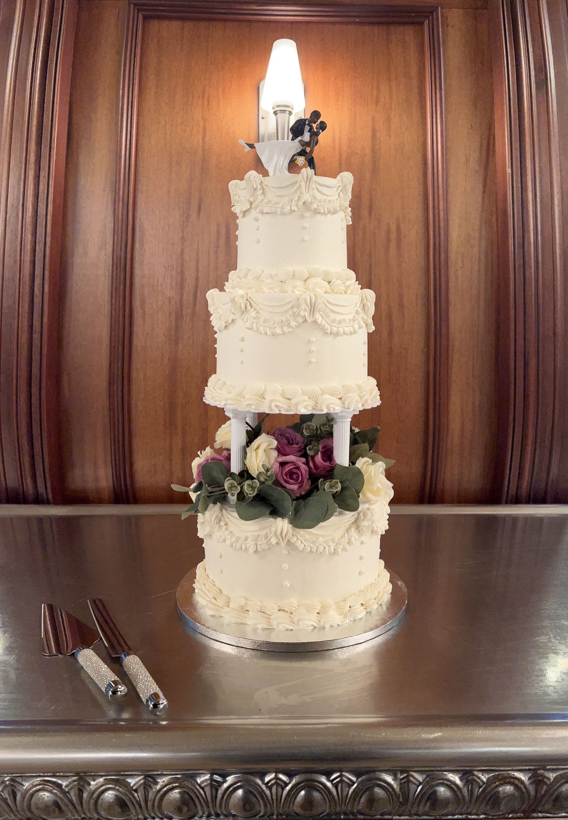 Tall white tiered wedding cake with floral decorations on a carved wooden table