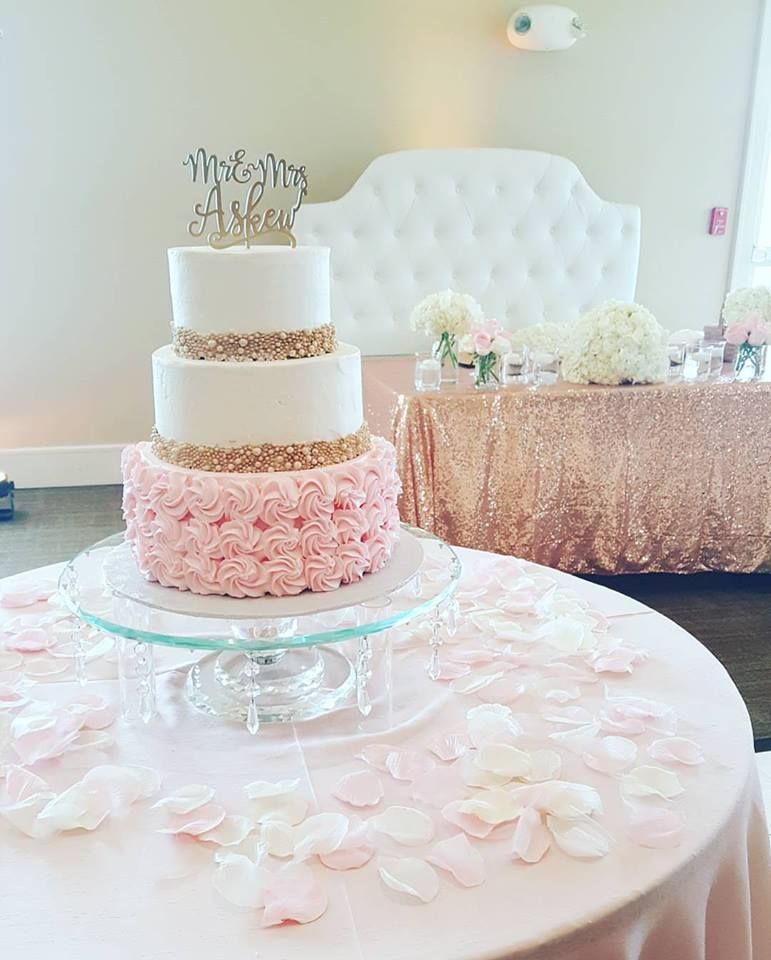 White tiered cake with pink floral accents on a decorated table at a pastel wedding reception