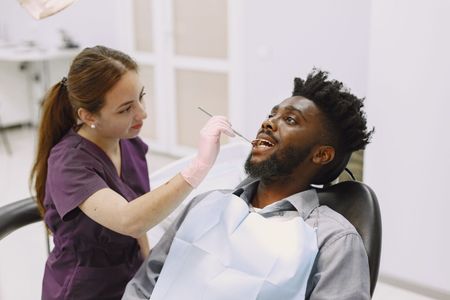 Dentist examining a smiling patient’s mouth in a bright clinic