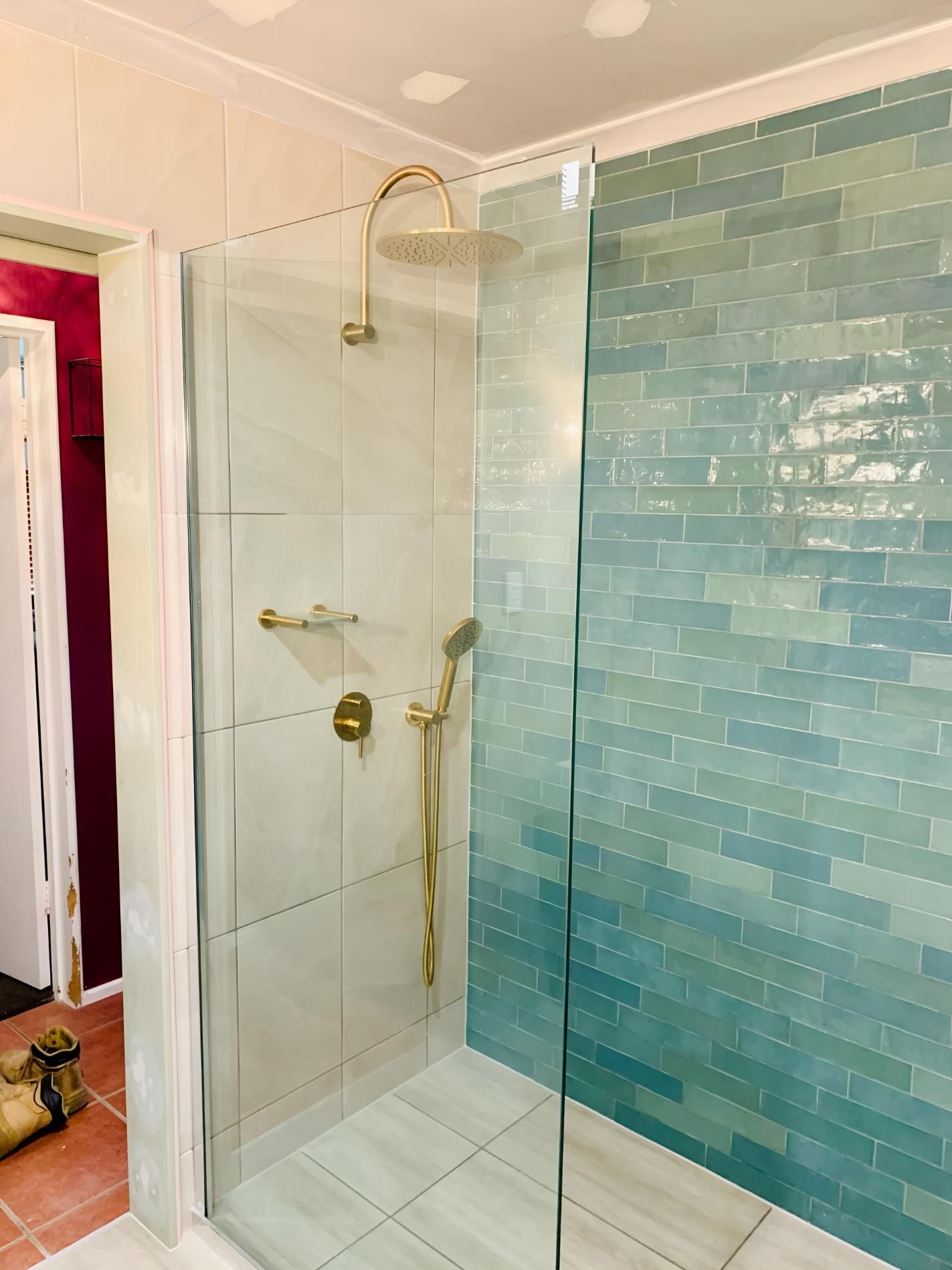 A Bathroom With Blue Tiles and a Walk in Shower With a Glass Door — Shane Firmin Carpentry Pty Ltd In Mount St John, QLD