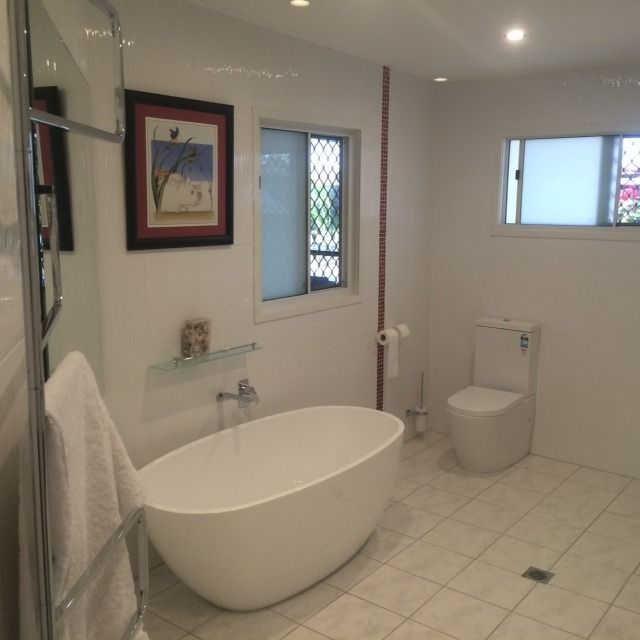 A Bathroom With a Bathtub Toilet and Window — Shane Firmin Carpentry Pty Ltd In Mount St John, QLD