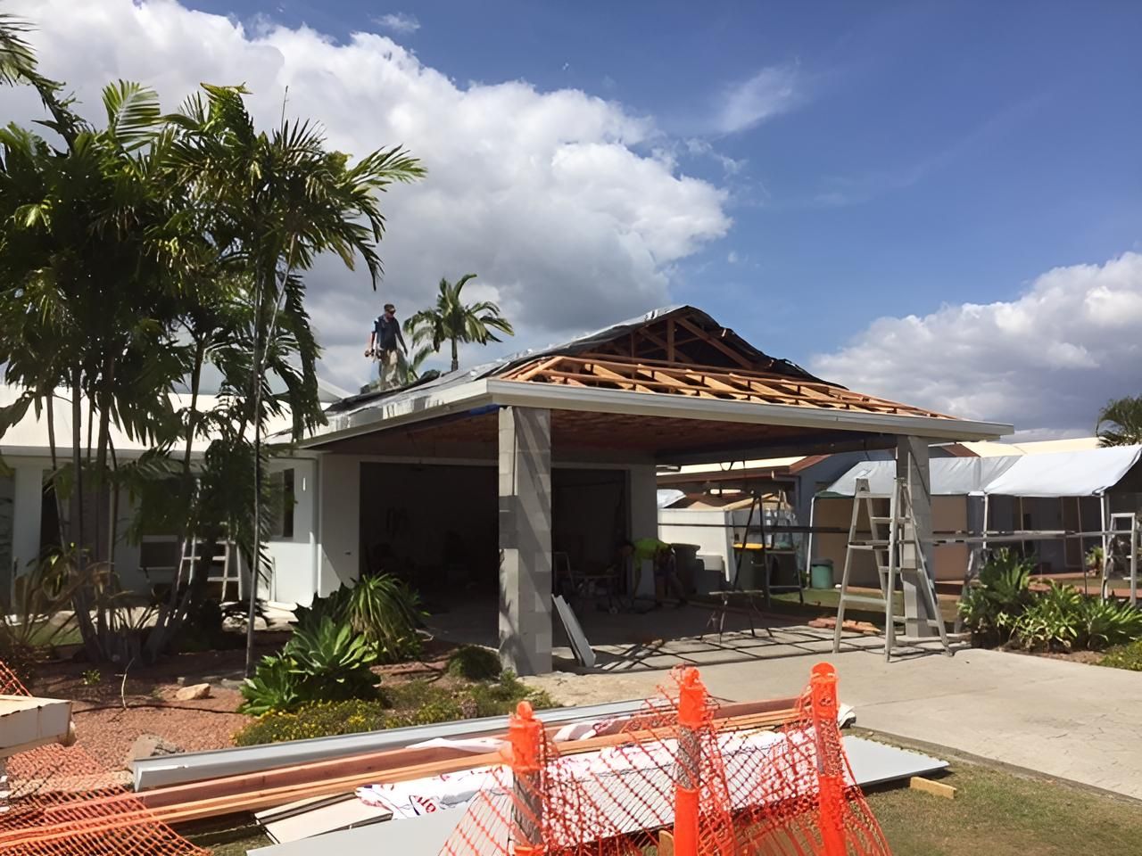 A Man is Standing on the Roof of a House Under Construction — Shane Firmin Carpentry Pty Ltd In Mount St John, QLD