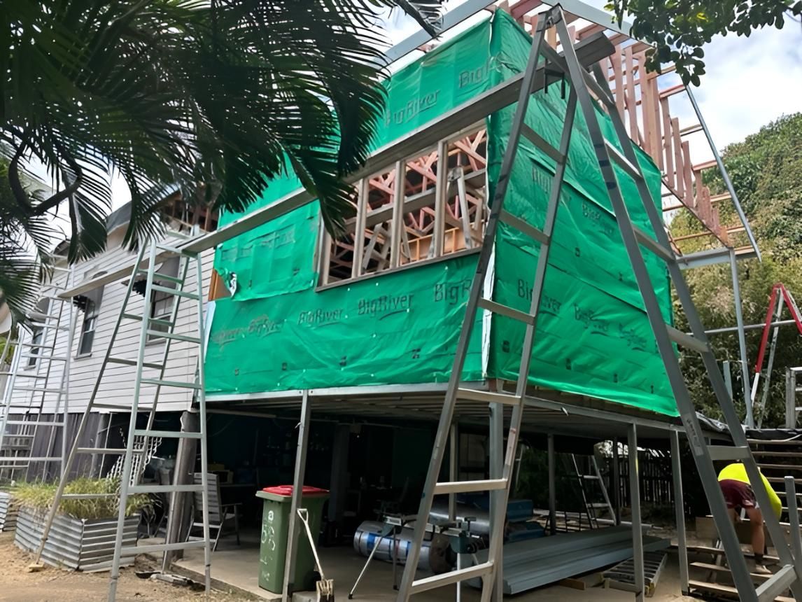 A House is Being Built With Scaffolding and a Green Tarp — Shane Firmin Carpentry Pty Ltd In Mount St John, QLD