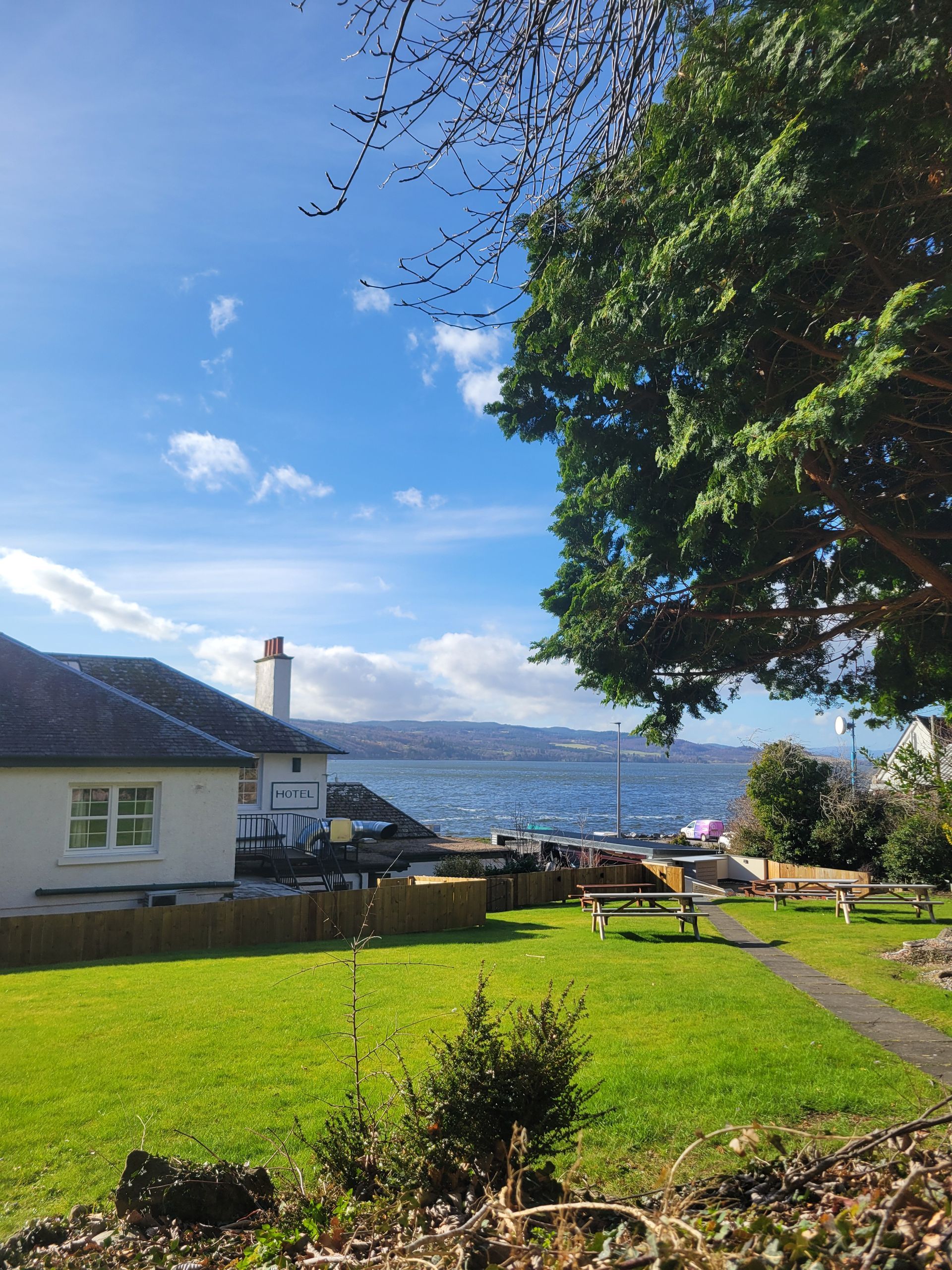 View of the Beauly Firth looking past the rear corner of the hotel from the garden with green grass and trees