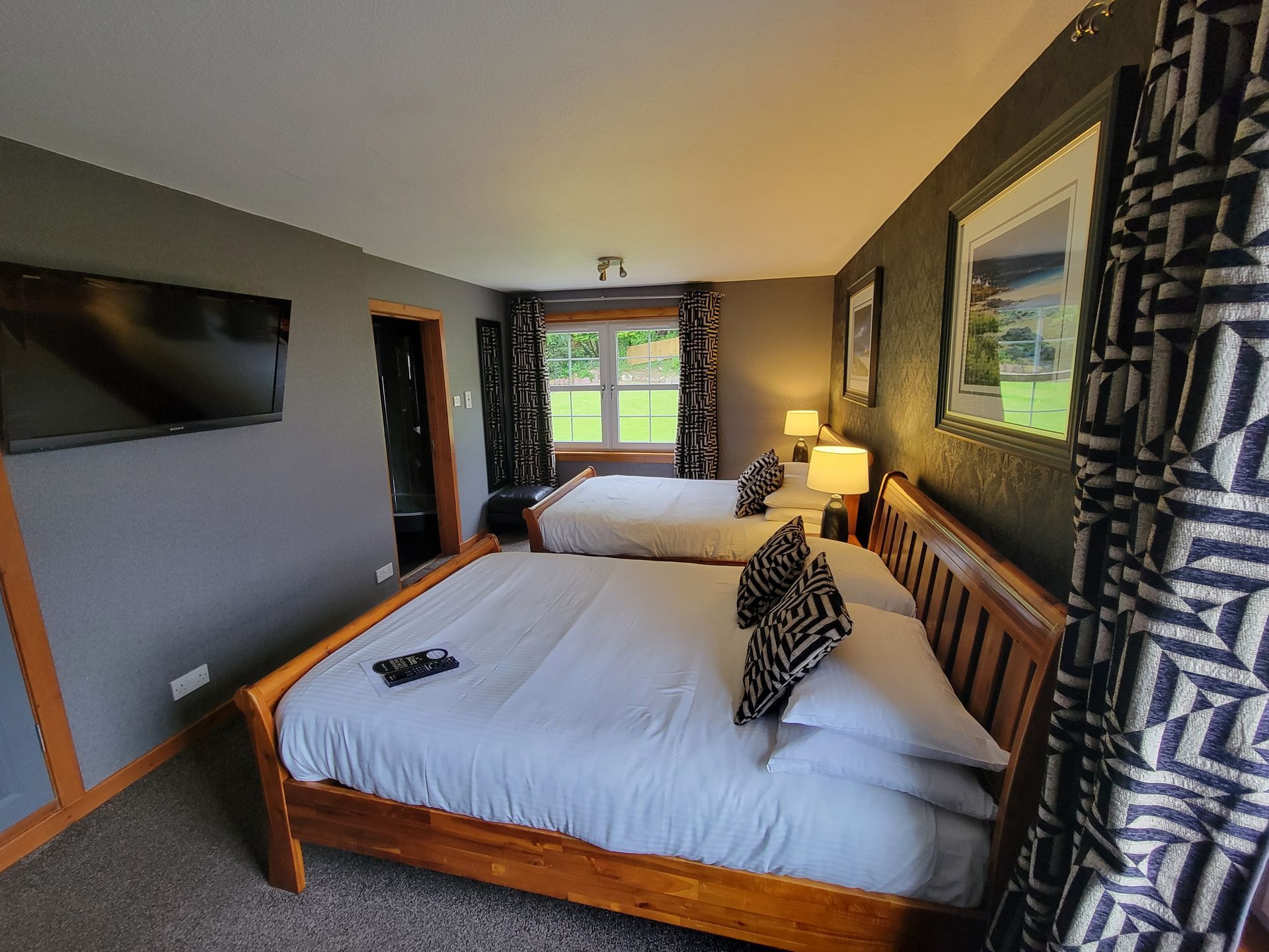 A hotel room with three beds and a television
