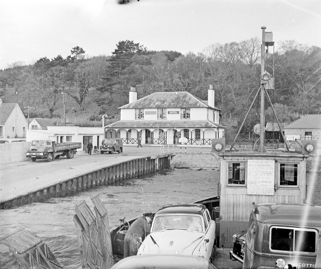 1940s photo of the hotel with the jetty and ferry in the water of the Beauly Firth, as well as old cars waiting to board