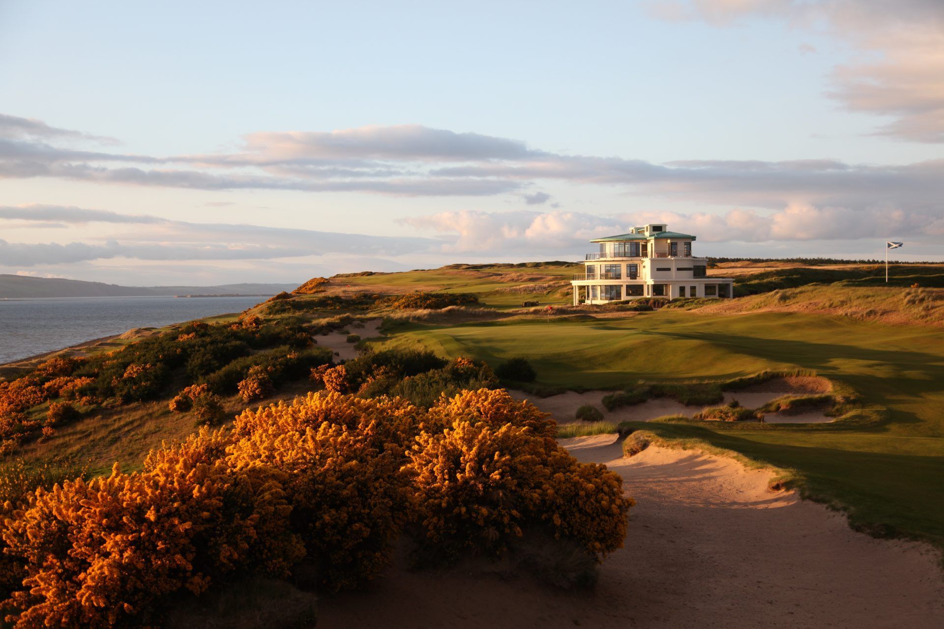 A house is sitting on top of a hill overlooking a golf course.