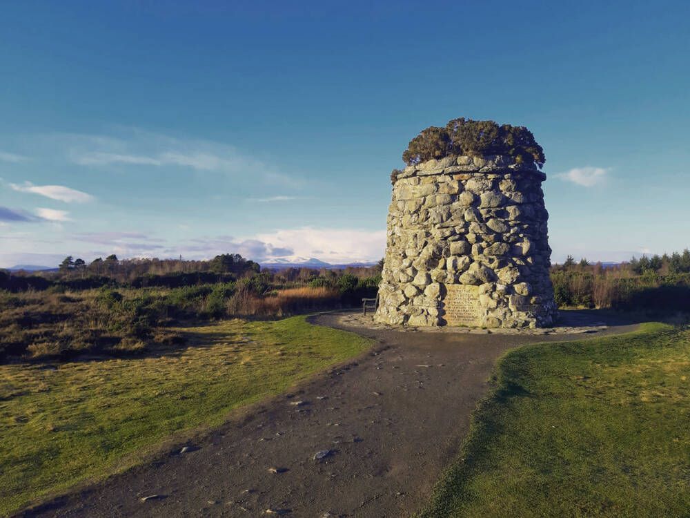 There is a large stone tower in the middle of a field.