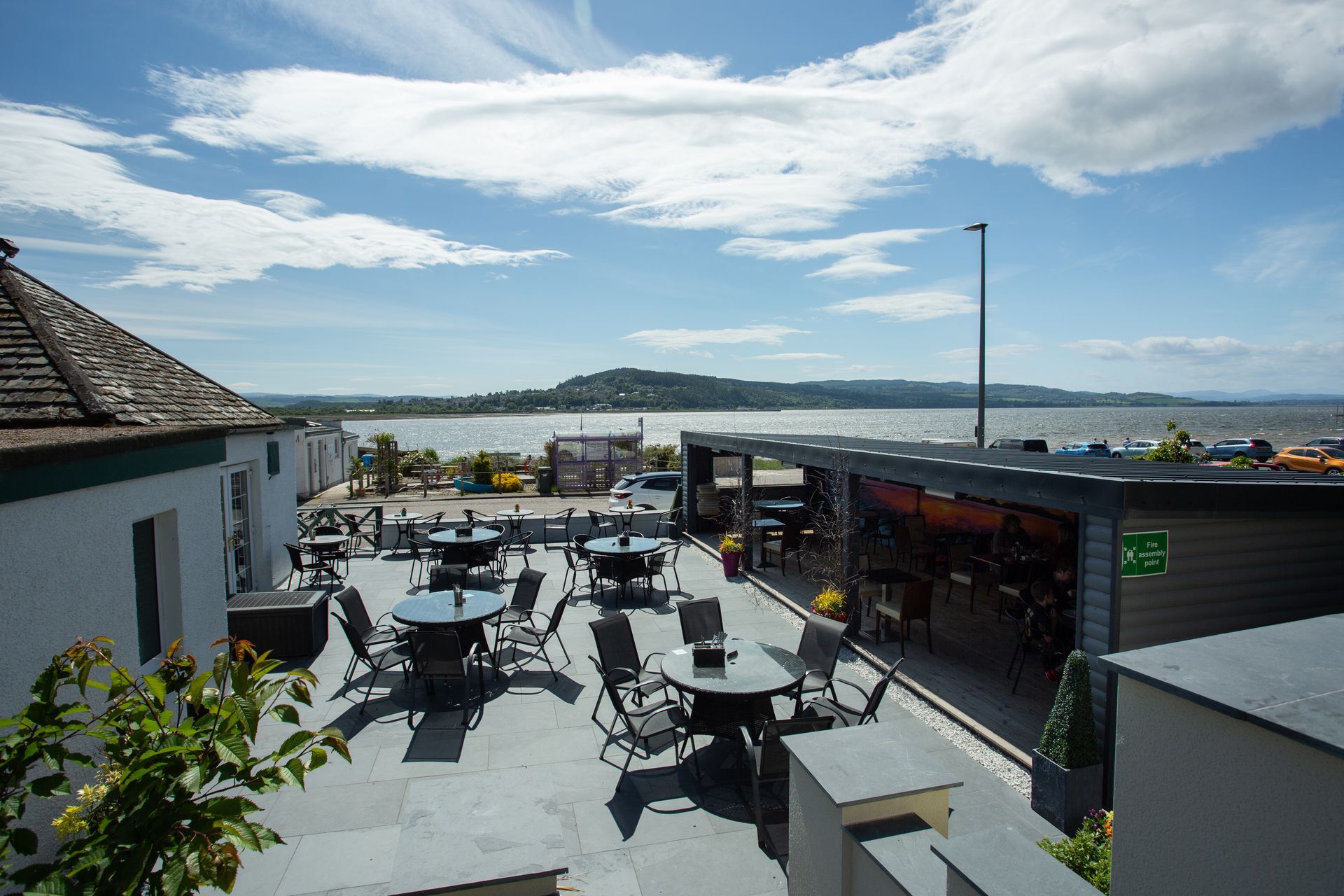 A patio with tables and chairs overlooking a body of water.