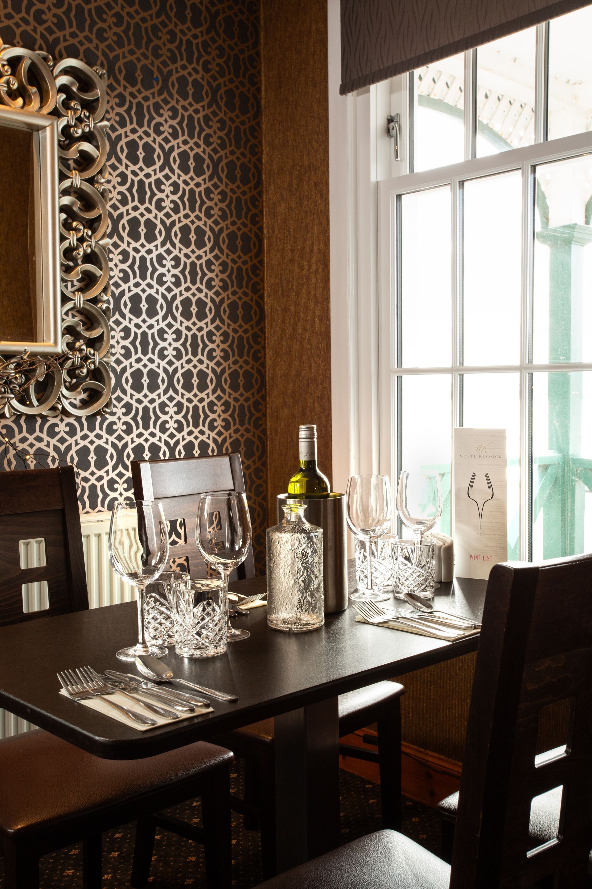 A dining room table with a bottle of wine and glasses on it.