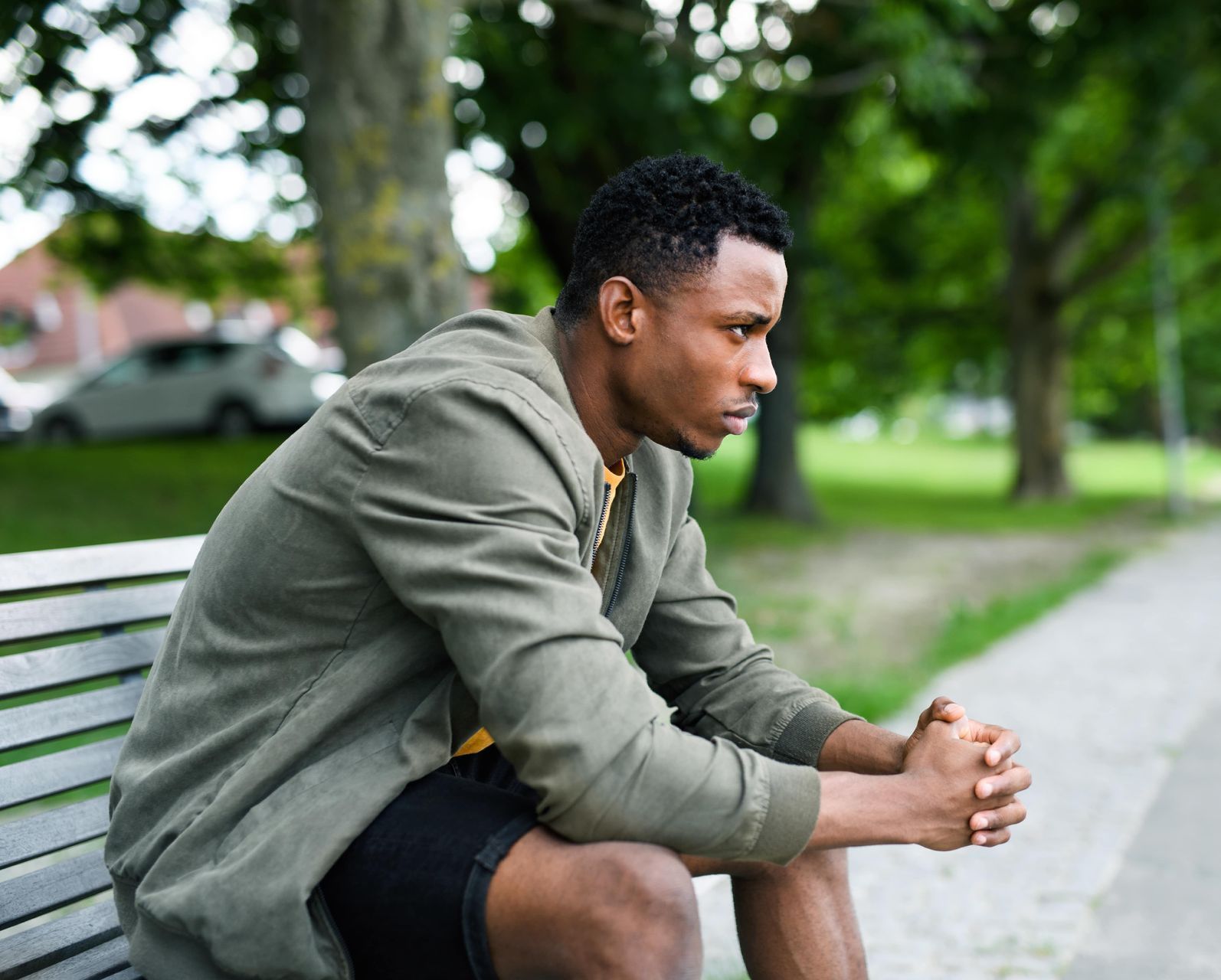 A young man is sitting on a park bench.