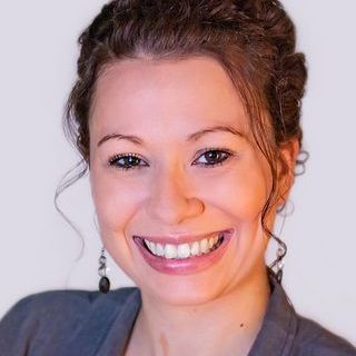 A woman with curly hair is smiling for the camera.