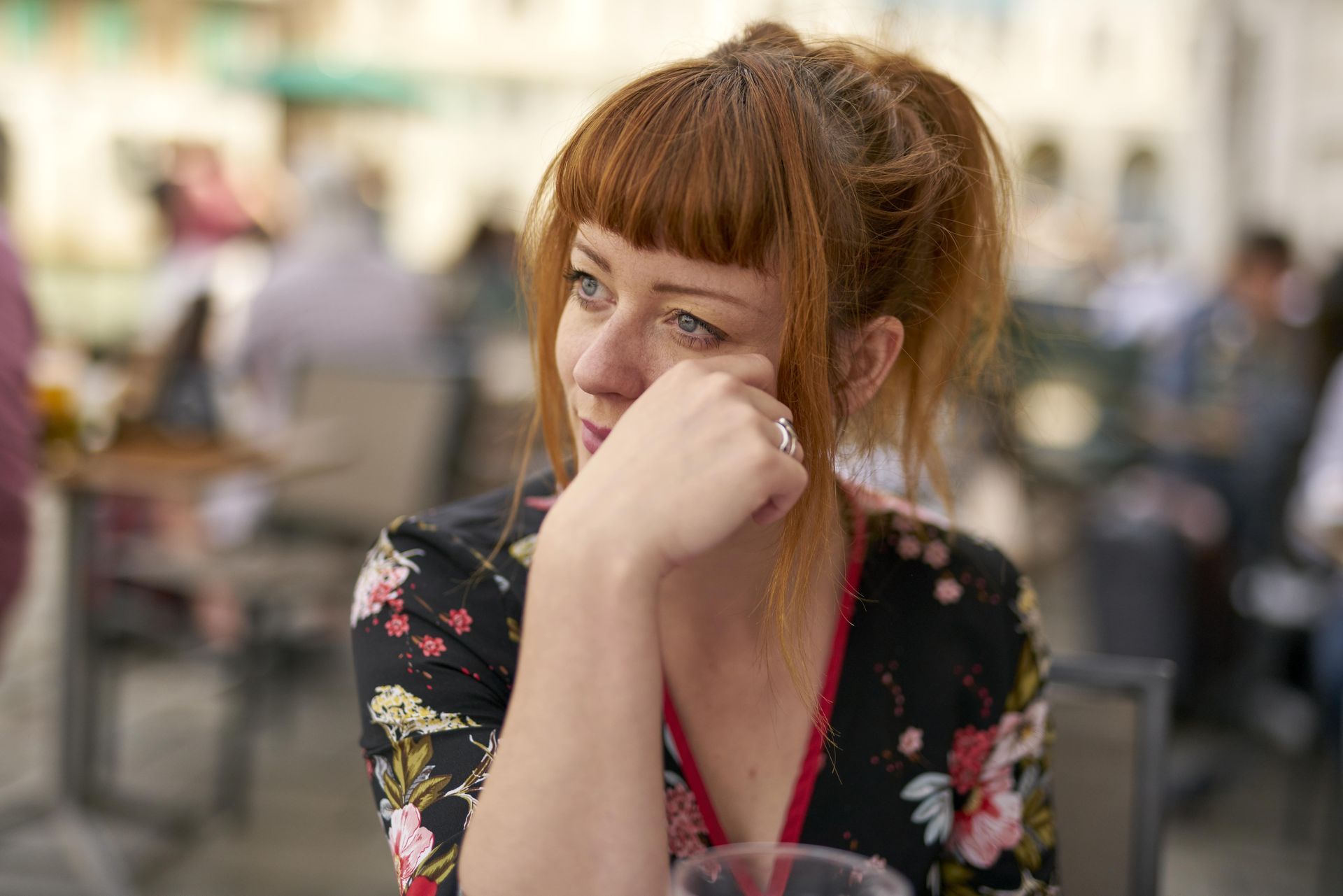 A woman is sitting at a table with her hand on her chin.