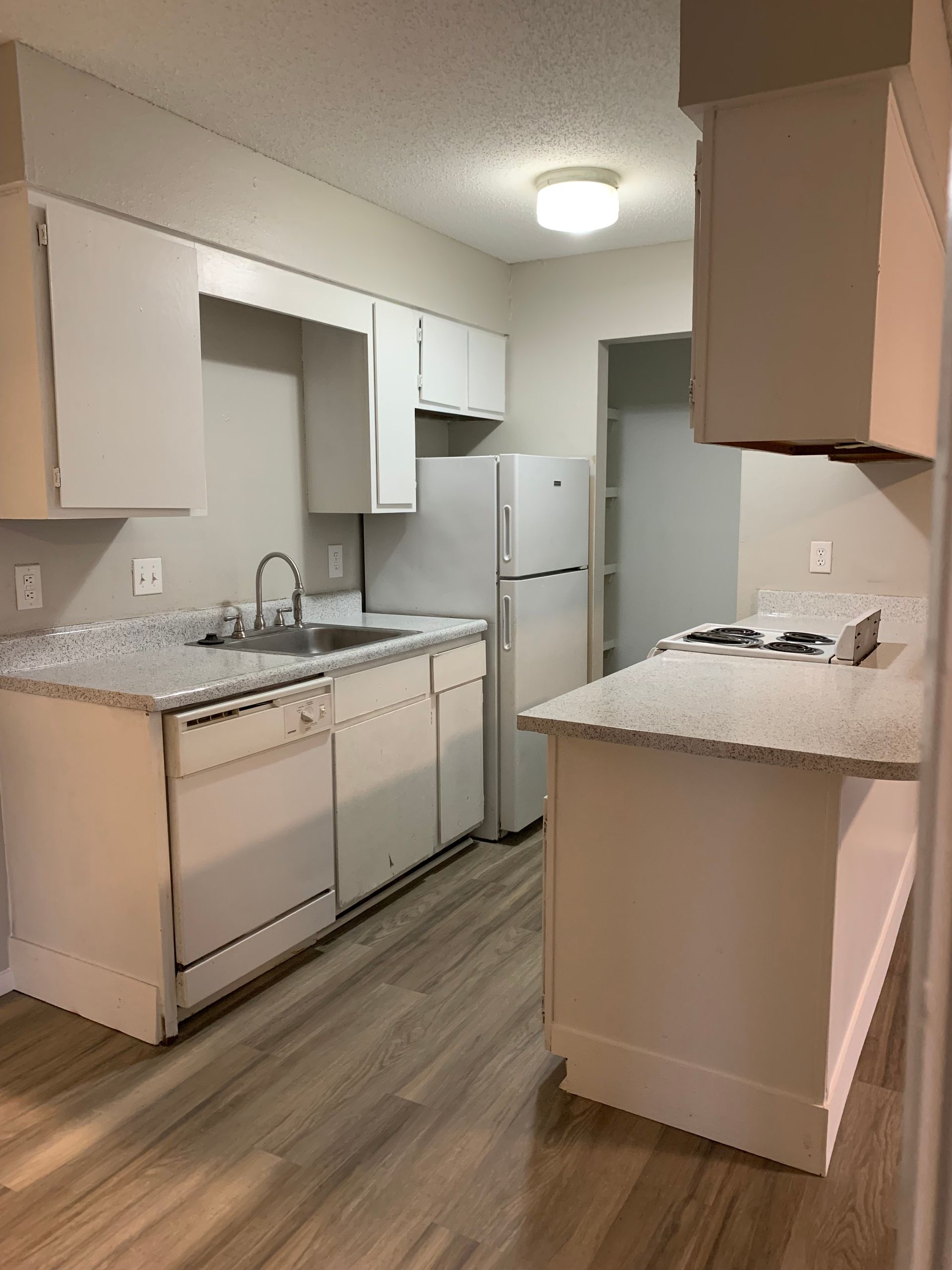 A kitchen with white cabinets , a refrigerator , a stove , a sink , and a dishwasher.