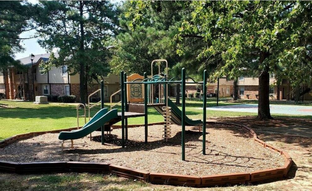 A playground with a slide and a climbing wall in a park.