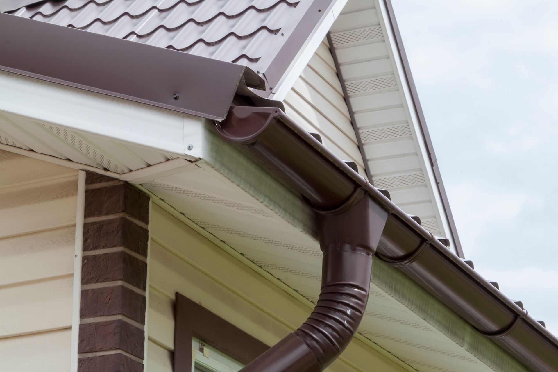 Close-up of a house's roof corner with a brown gutter system.