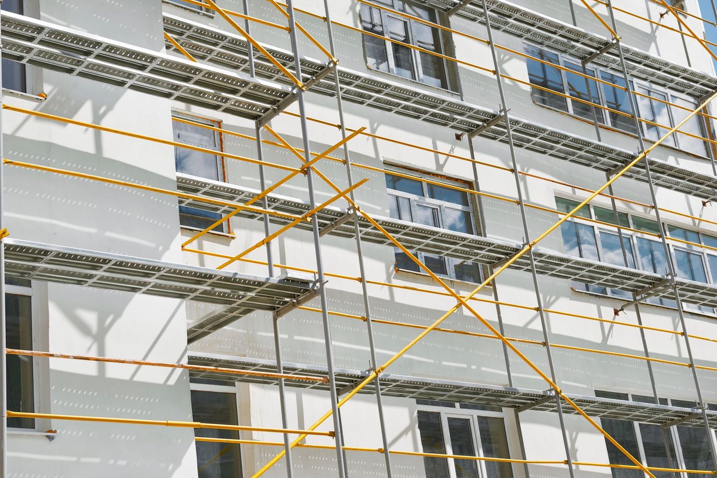 Cantiere edile con edifici in cemento e alte gru sotto un cielo azzurro e limpido.