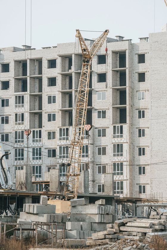Grattacieli in costruzione con gru a torre sullo sfondo di un cielo azzurro e limpido.