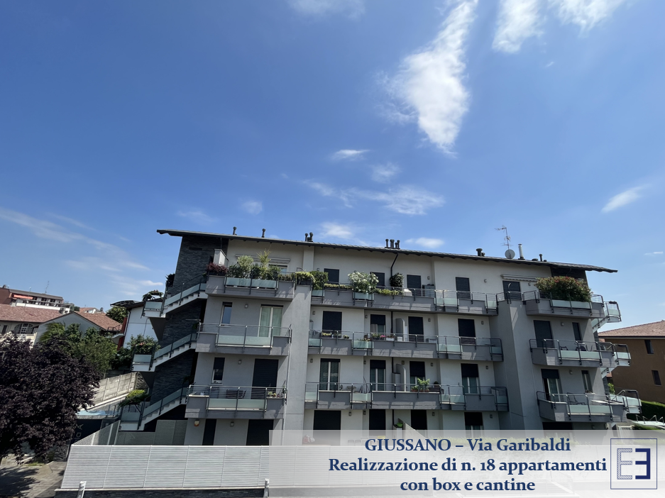 Edificio residenziale sotto un cielo azzurro con nuvole bianche, caratterizzato da balconi e un'insegna Realizzazione di n. 15 appartamenti.