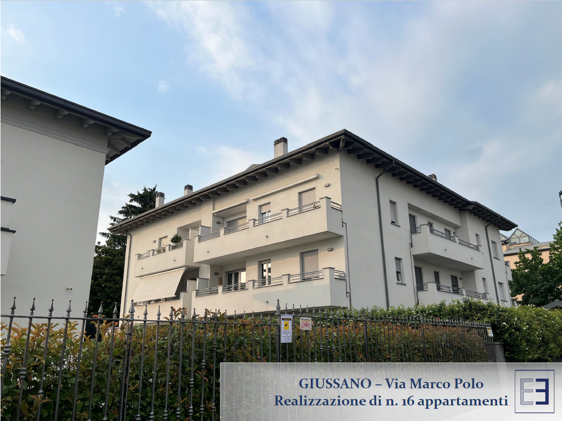Veduta stradale di un palazzo di appartamenti beige con balconi e un'insegna con la scritta 