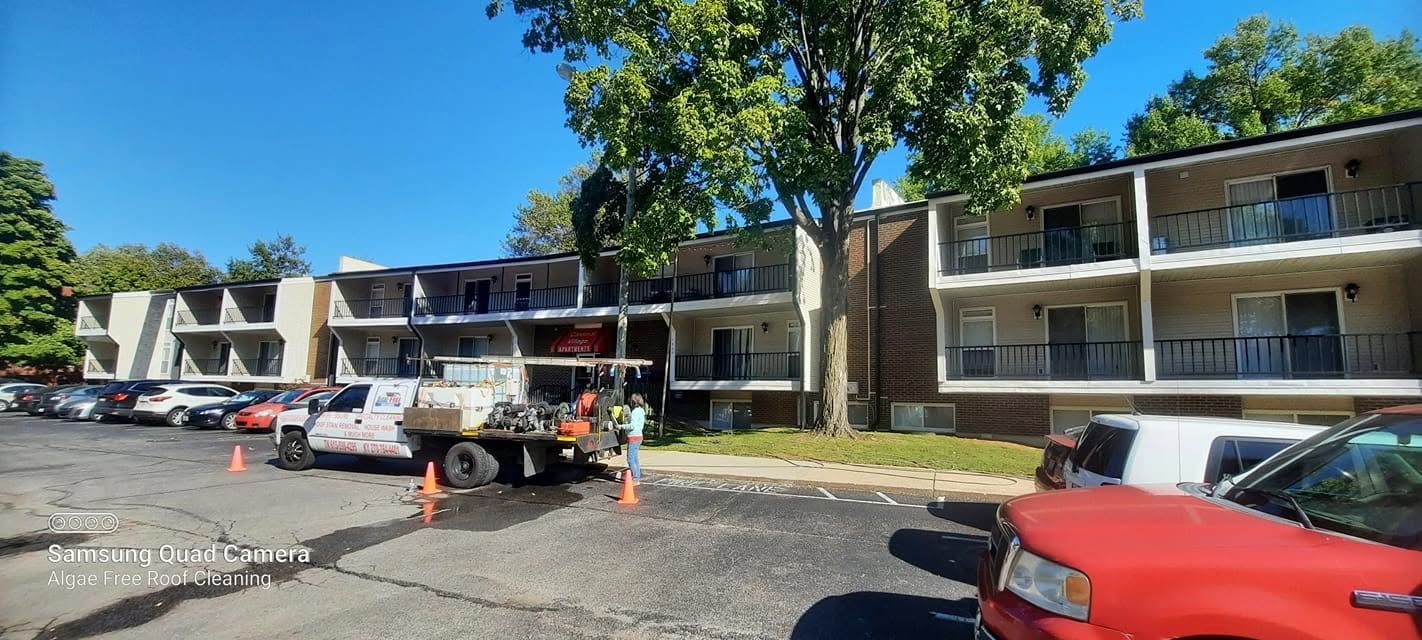 Apartment complex parking lot with cars, orange cones, and a truck under a blue sky