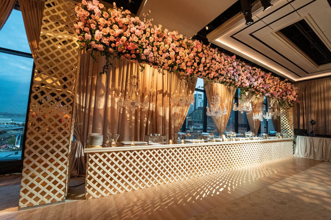 a long buffet line in a large room with flowers hanging from the ceiling .