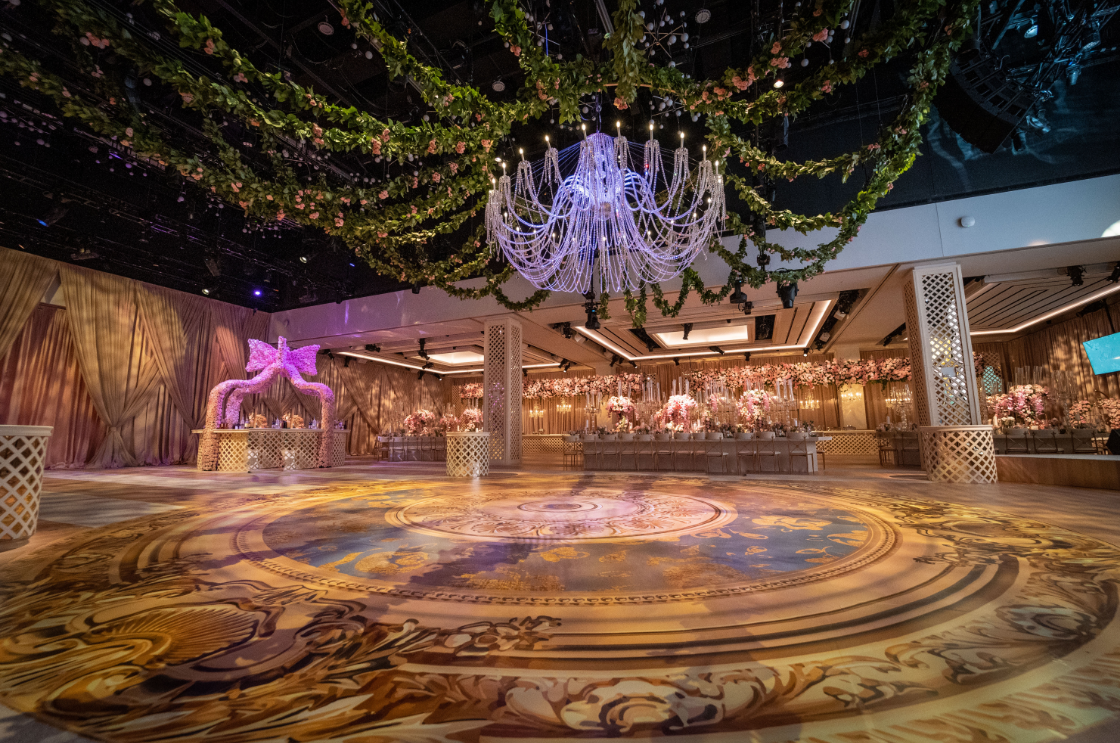 A large room with a circular dance floor and a chandelier hanging from the ceiling.