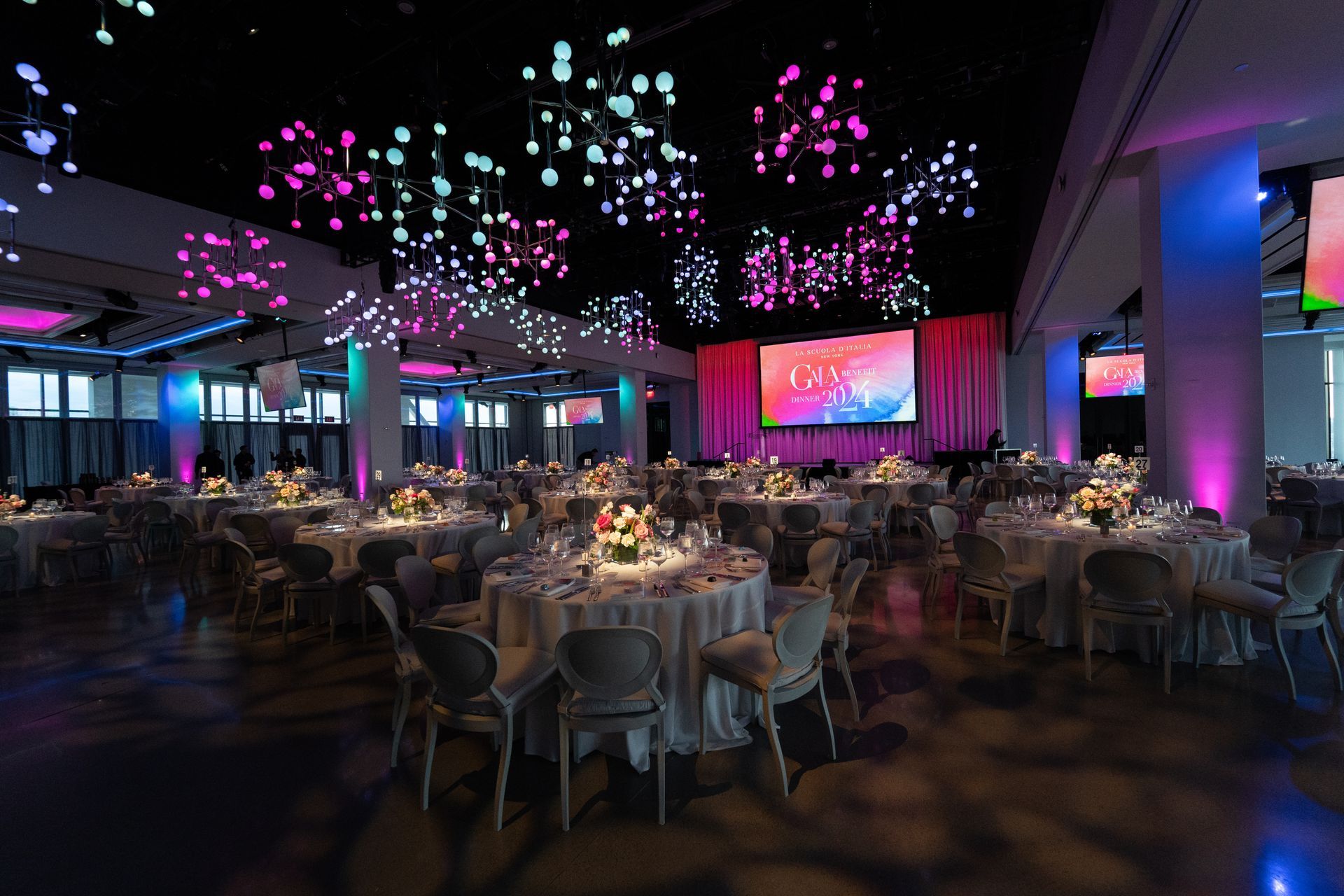 A large room filled with tables and chairs and a large screen.