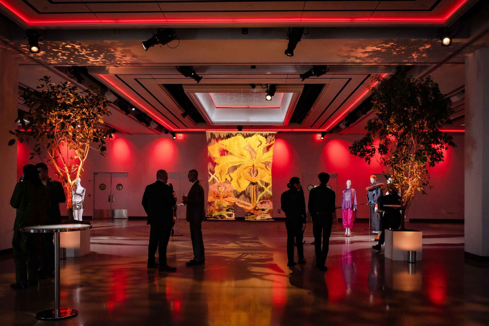a group of people are standing in a room with red lights .