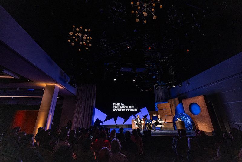 Audience watching speakers on a stage with the text 