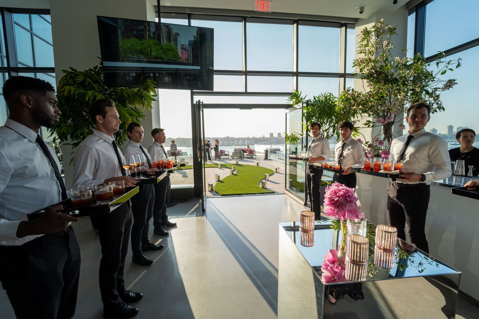 a group of men are standing in a room holding trays of drinks .