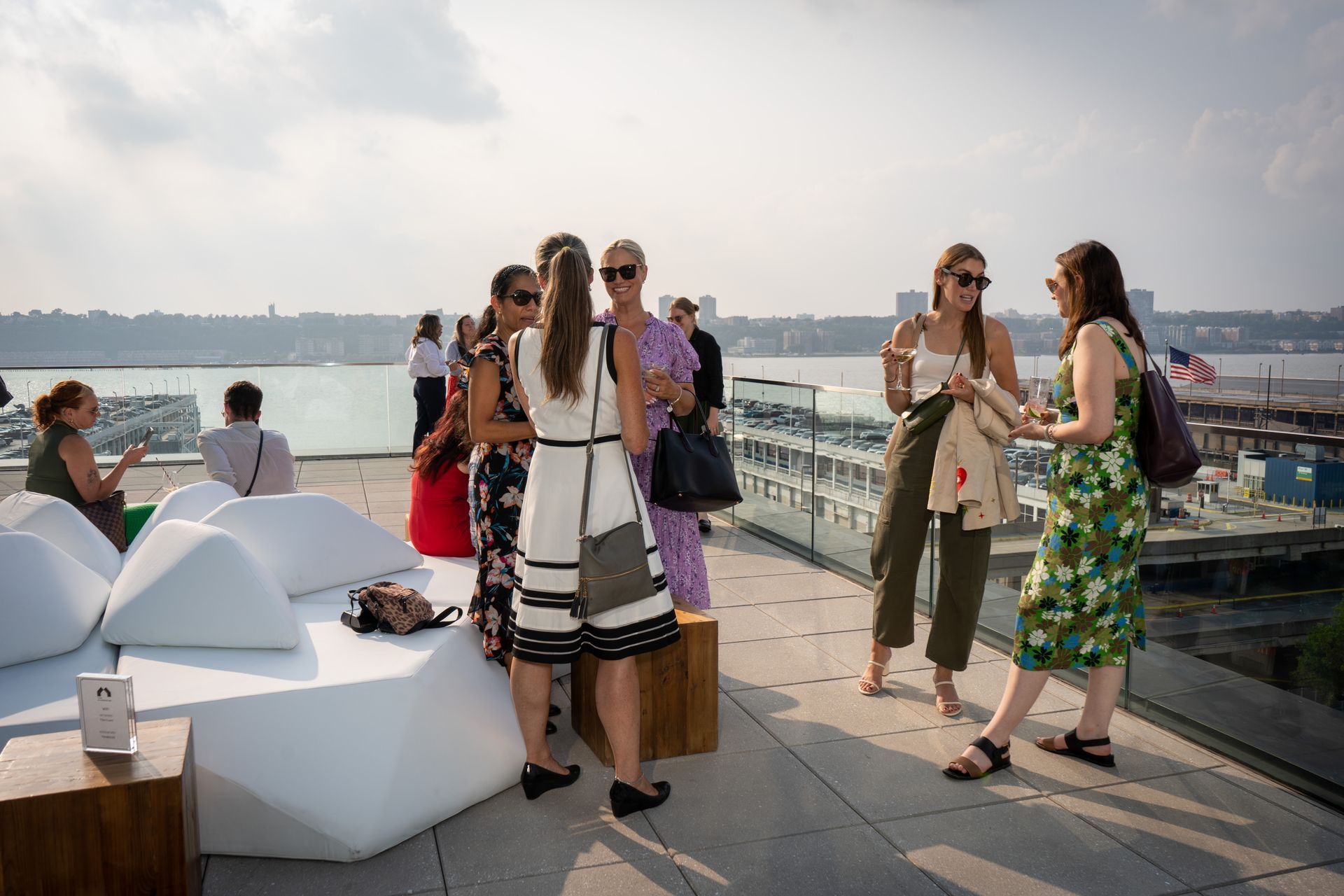 A group of women are standing on a rooftop talking to each other.