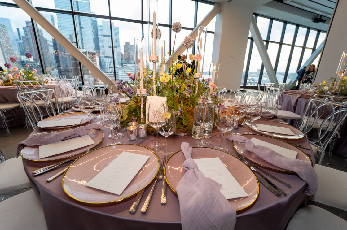 a table set for a wedding reception with plates , utensils , and flowers on it .